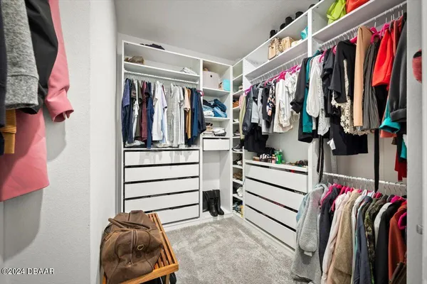 a view of walk in closet with clothes and shoes