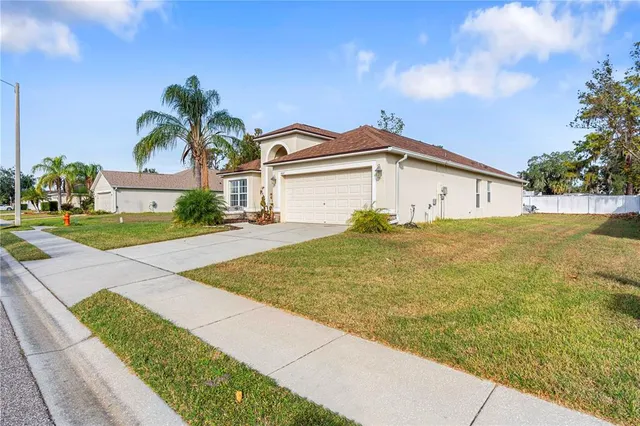 a view of a white house with a yard and palm trees