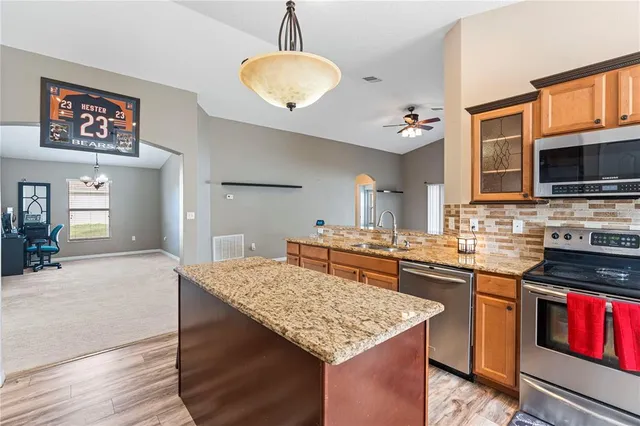 a kitchen with kitchen island granite countertop a stove cabinets and wooden floor