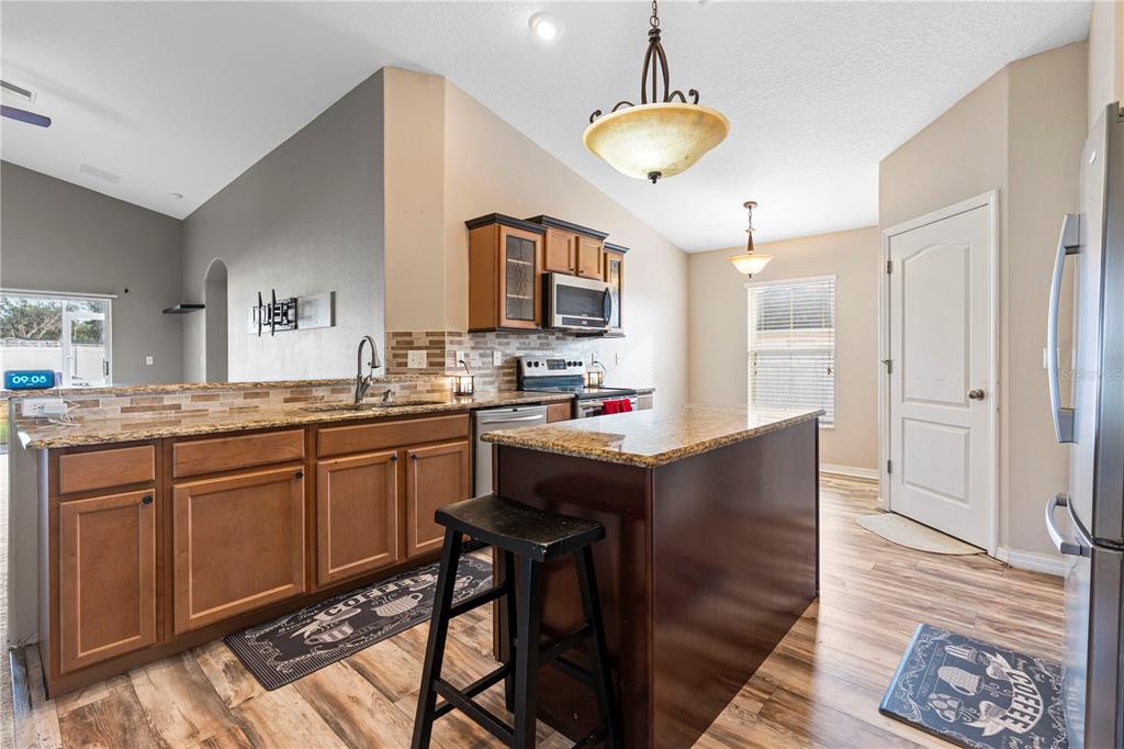 4667 Hickory Stream Lane Mulberry, FL 33860 - Photo 9 of 41 a kitchen with stainless steel appliances granite countertop a refrigerator a sink dishwasher a stove and a dining table with wooden floor