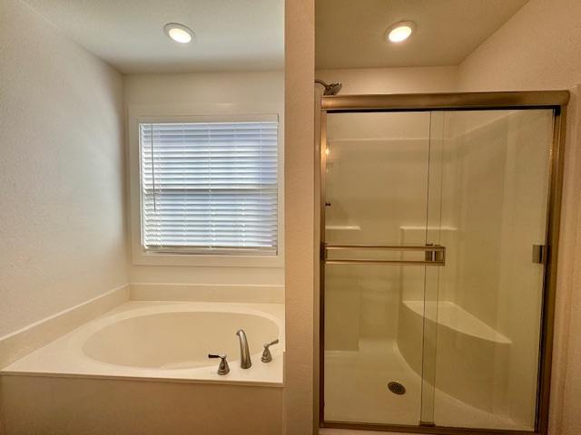 2250 Hunter Drive Pea Ridge, AR 72751 - Photo 13 of 21 Built-in soaking tub with deck-mounted faucet, window with blinds, and glass-enclosed shower with integrated bench
