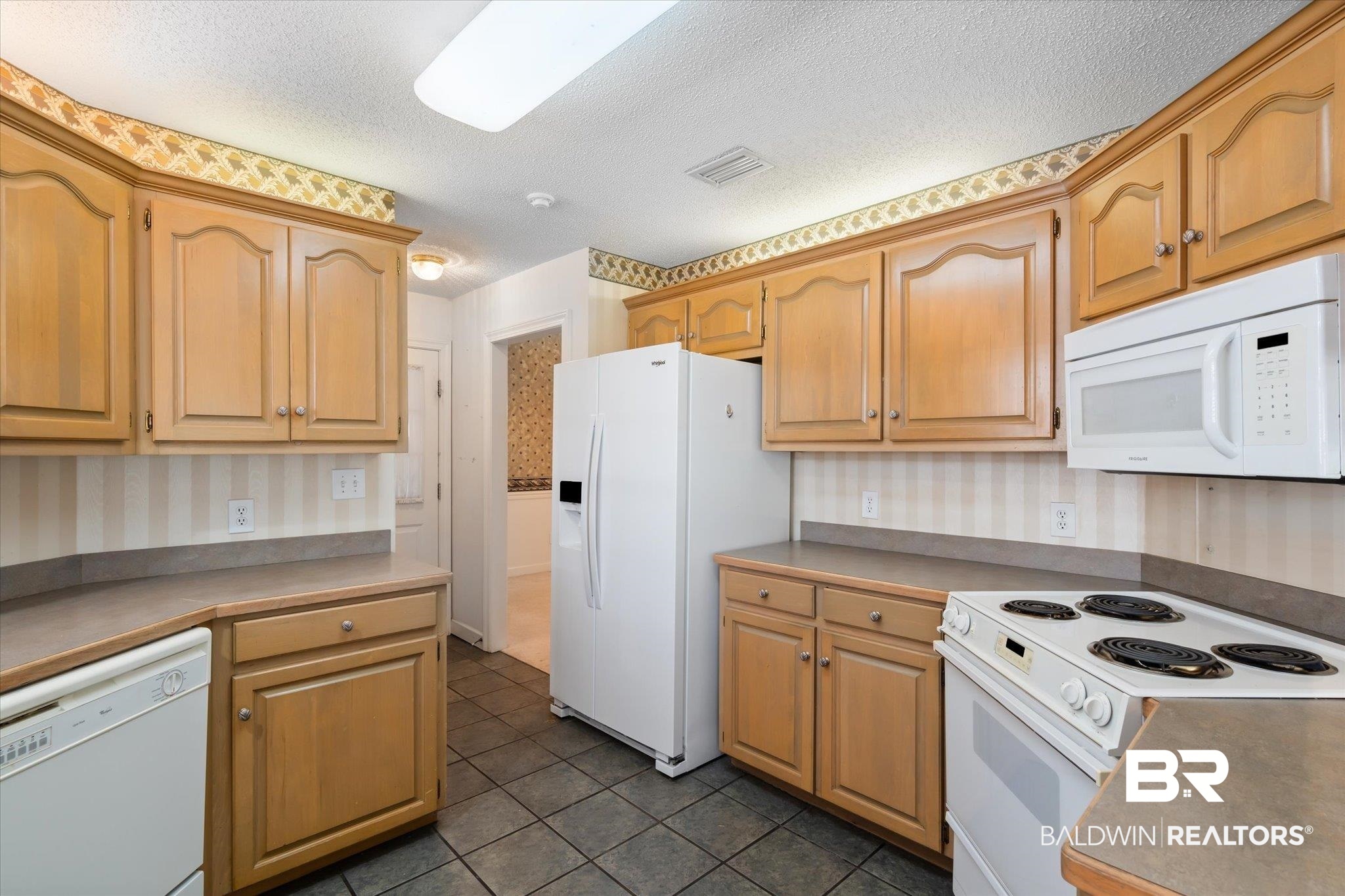 2220 Irongate Court Mobile, AL 36695 - Photo 5 of 20 Kitchen with white appliances, wallpapered walls, visible vents, dark tile patterned flooring, and a textured ceiling