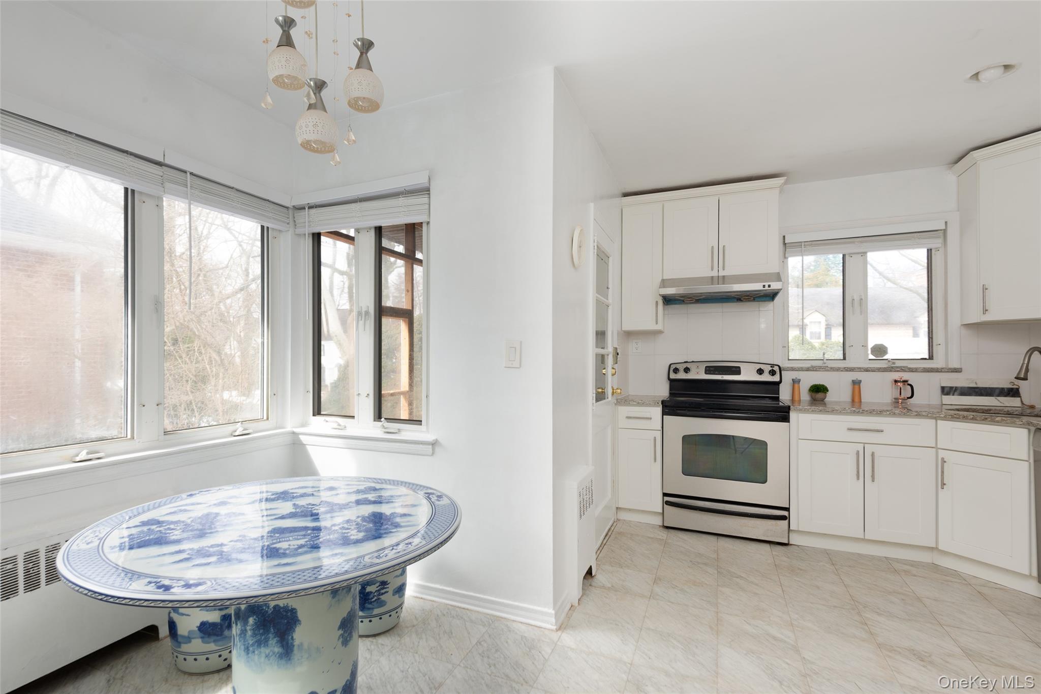200 Melbourne Road Great Neck, NY 11021 - Photo 9 of 24 a kitchen with stainless steel appliances a sink a stove a table and chairs