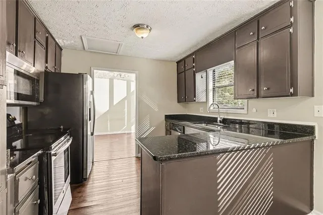 a kitchen with granite countertop a sink stove and refrigerator