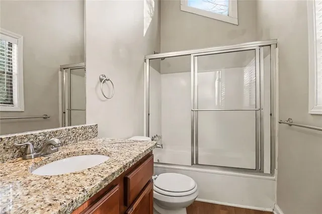 a bathroom with a granite countertop sink toilet and shower