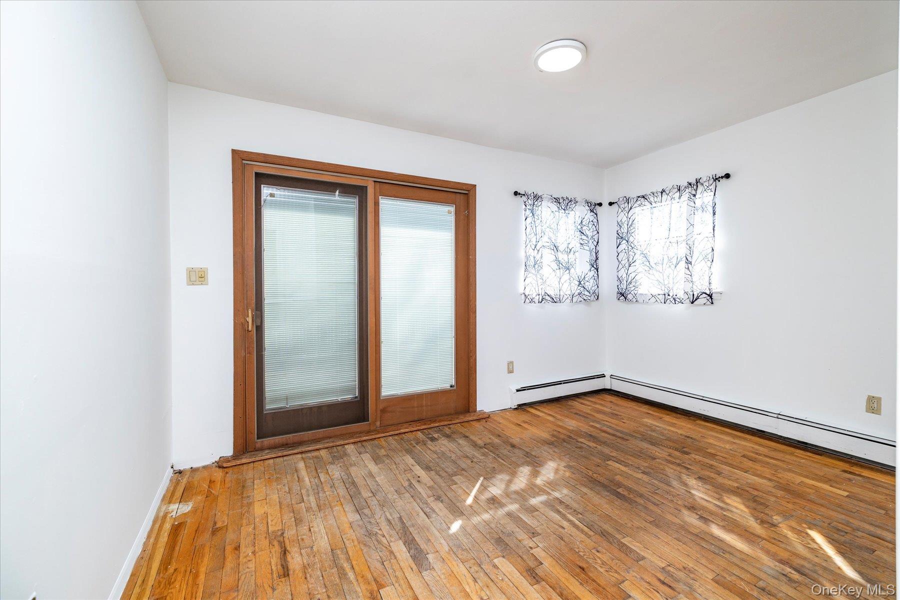 112 Chestnut Street Lynbrook, NY 11563 - Photo 10 of 13 an empty room with wooden floor and windows