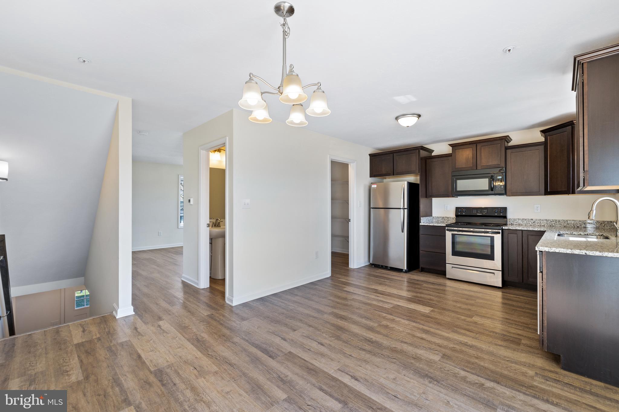 0 H Street, Unit 111 Carlisle, PA 17013 - Photo 4 of 26 a view of a kitchen with stainless steel appliances granite countertop a refrigerator a sink dishwasher a stove and a wooden floor