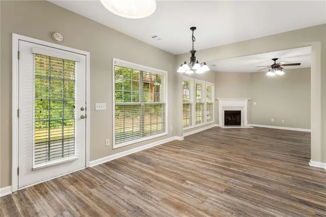 a view of an empty room with wooden floor fireplace and a window