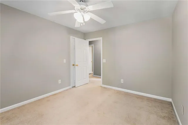 an empty room with a chandelier fan and closet area