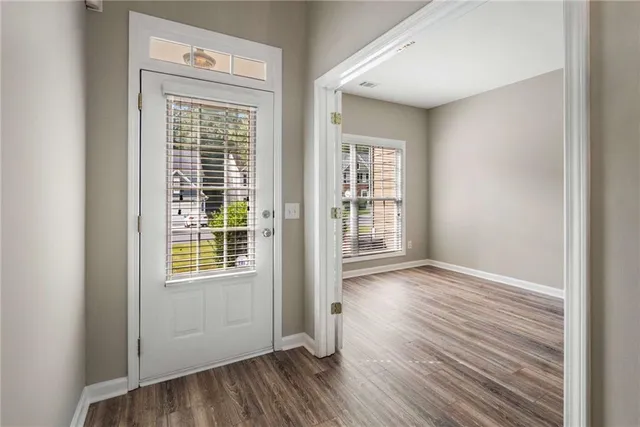 an empty room with wooden floor and windows
