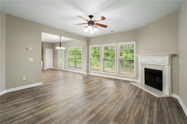 a view of an empty room with wooden floor fireplace and a window