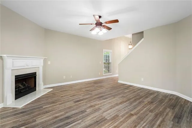 a view of an empty room with wooden floor fireplace and a window