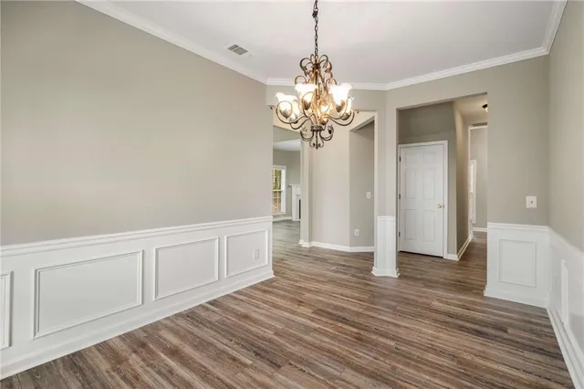 a view of a hallway with wooden floor and chandelier