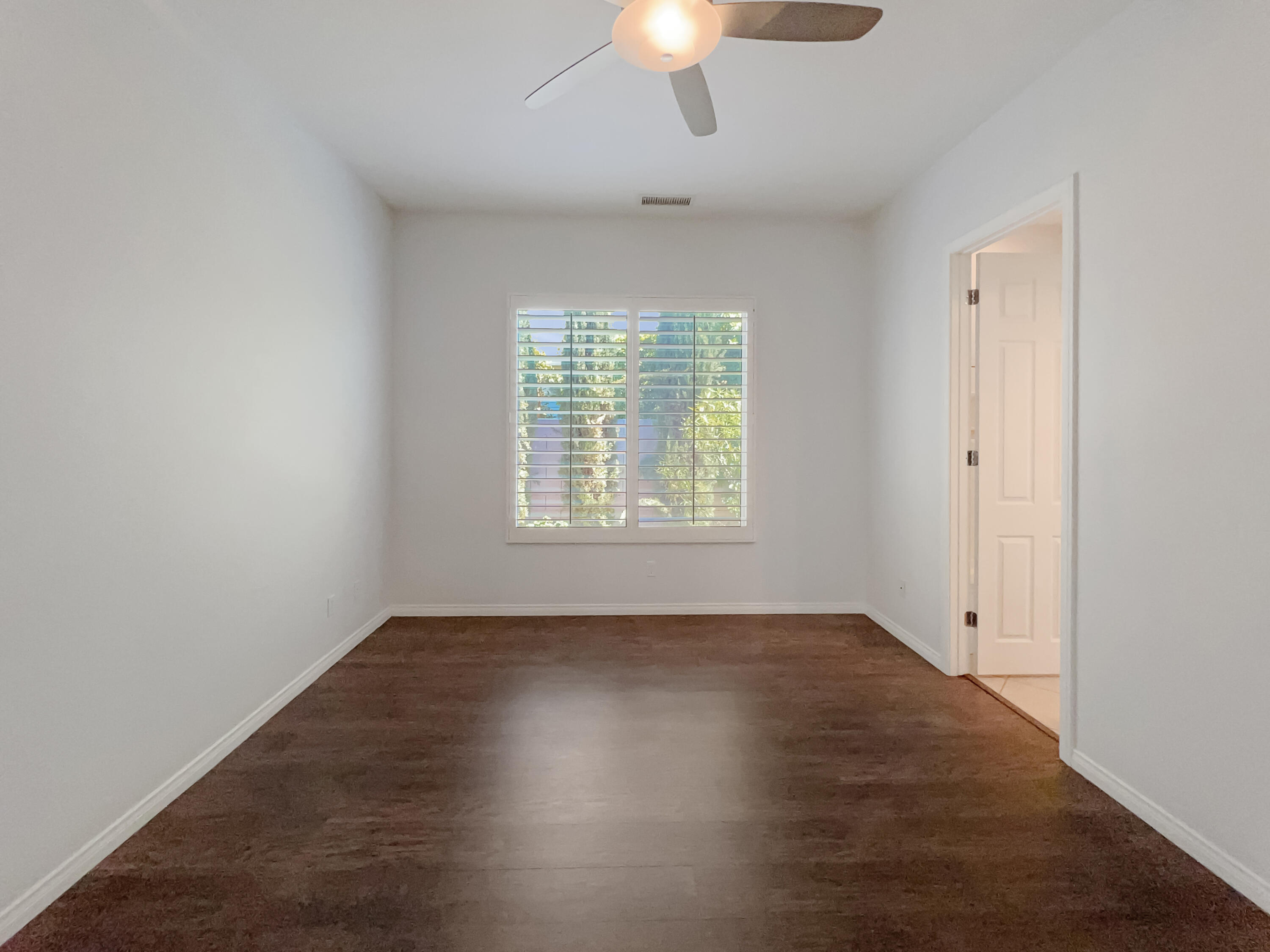 5 Lyon Road Rancho Mirage, CA 92270 - Photo 21 of 36 an empty room with wooden floor chandelier fan and windows