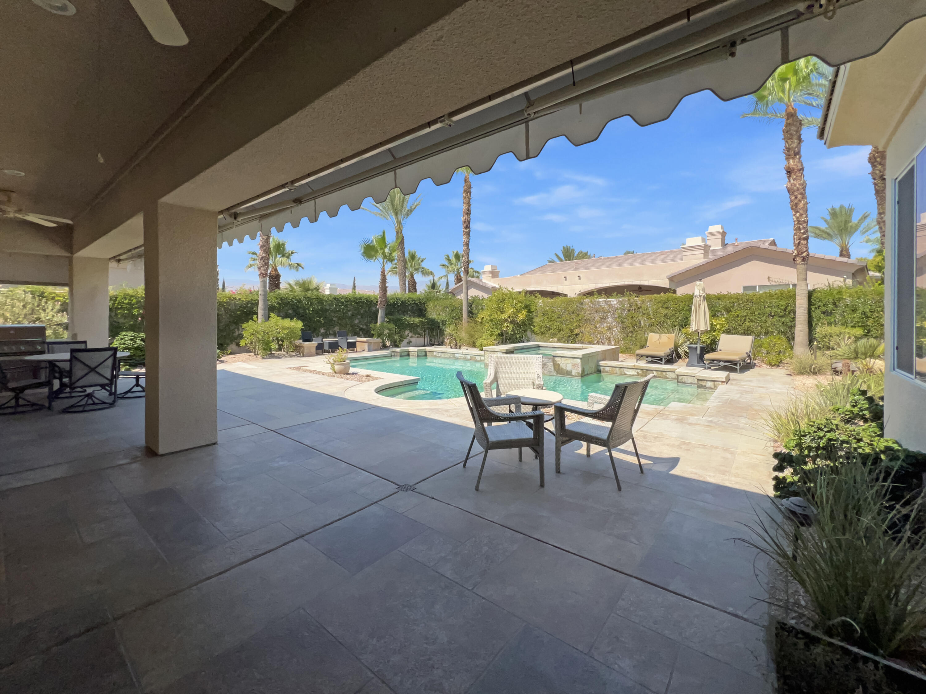 5 Lyon Road Rancho Mirage, CA 92270 - Photo 22 of 36 a view of a patio with a table chairs and a floor to ceiling window
