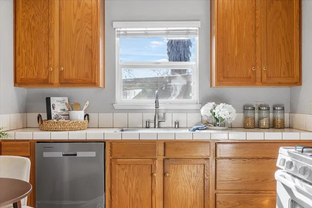 a kitchen with granite countertop a sink stainless steel appliances white cabinets and a window