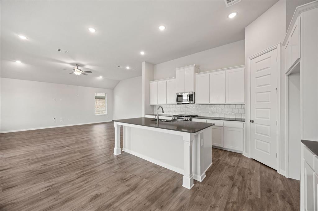 1506 Red Clover Avenue Van Alstyne, TX 75495 - Photo 8 of 24 a kitchen with stainless steel appliances wooden floors and white cabinets