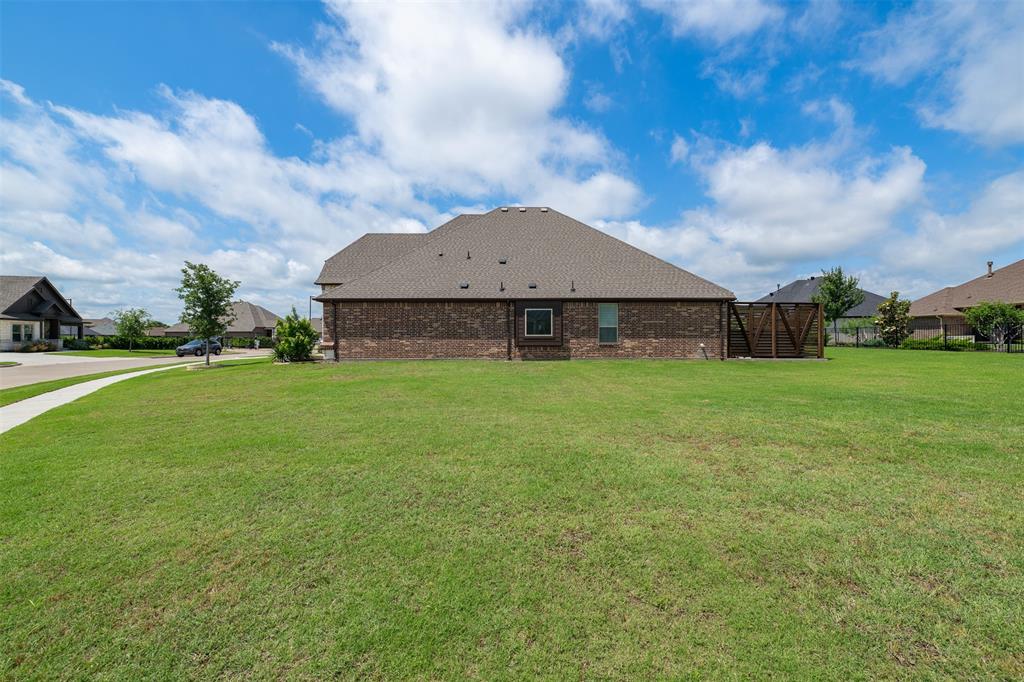 2011 Spieth Street Granbury, TX 76048 - Photo 34 of 35 Back of house with a lawn, brick siding, and roof with shingles