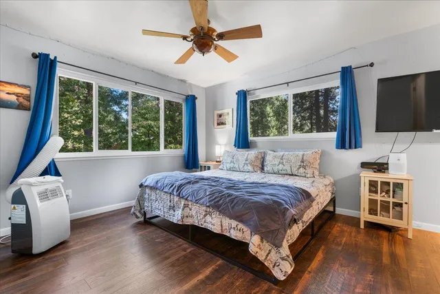 a bedroom with a large bed a flat tv screen and a dresser