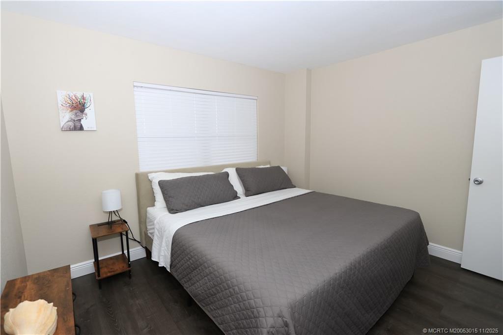 7380 South Ocean Drive, Unit 621 Jensen Beach, FL 34957 - Photo 32 of 48 a bed sitting in a bedroom next to a window with wooden floor