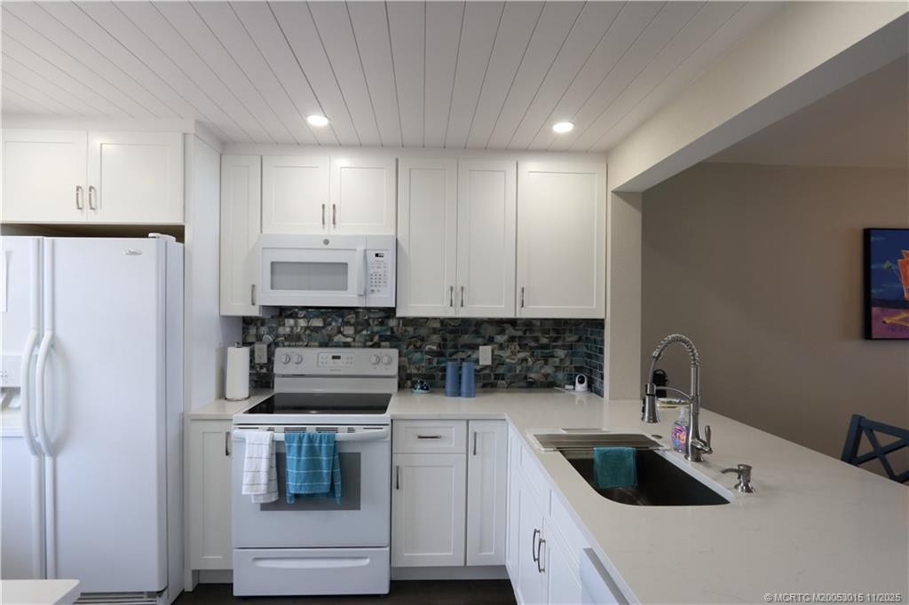 7380 South Ocean Drive, Unit 621 Jensen Beach, FL 34957 - Photo 4 of 48 a kitchen with white cabinets and refrigerator