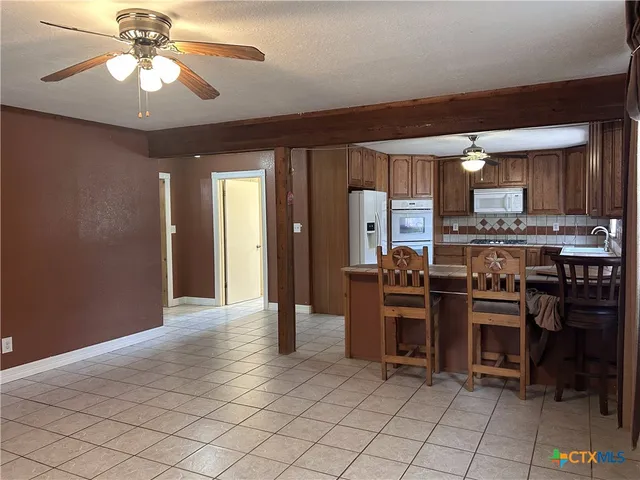 a view of an empty room with chandelier fan and a window
