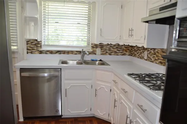a kitchen with white cabinets and appliances