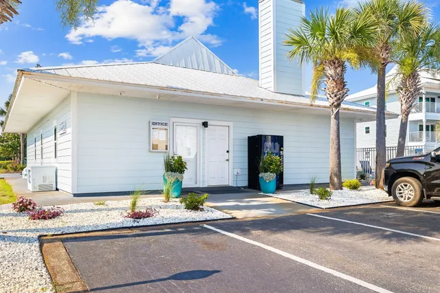 a view of a house with cars park side of a road