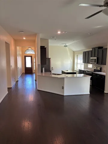 a view of a kitchen with a sink wooden cabinets and a window