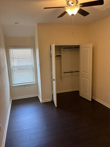 an empty room with wooden floor cabinet and windows