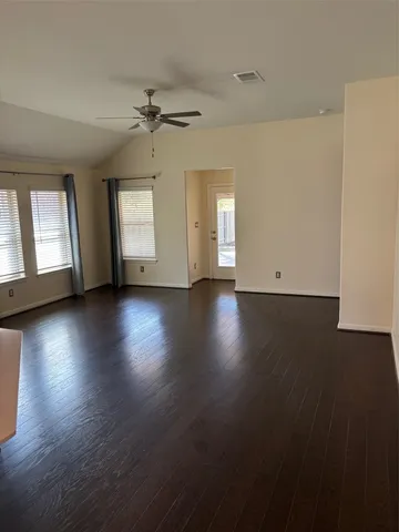 an empty room with wooden floor and windows