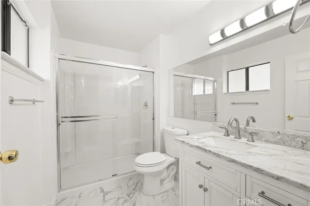 a bathroom with a granite countertop sink toilet and shower