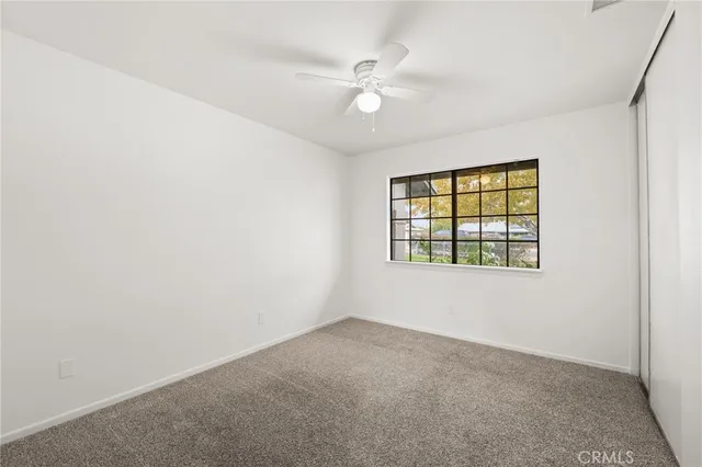 an empty room with windows and ceiling fan