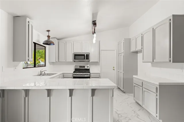 a kitchen with stainless steel appliances a stove a sink a refrigerator white cabinets and wooden floor