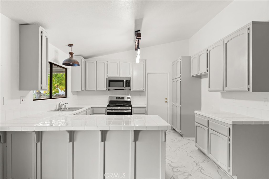 17805 Walnut Street Hesperia, CA 92345 - Photo 5 of 18 a kitchen with stainless steel appliances a stove a sink a refrigerator white cabinets and wooden floor