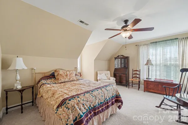 a bedroom with a bed a chair and a chandelier