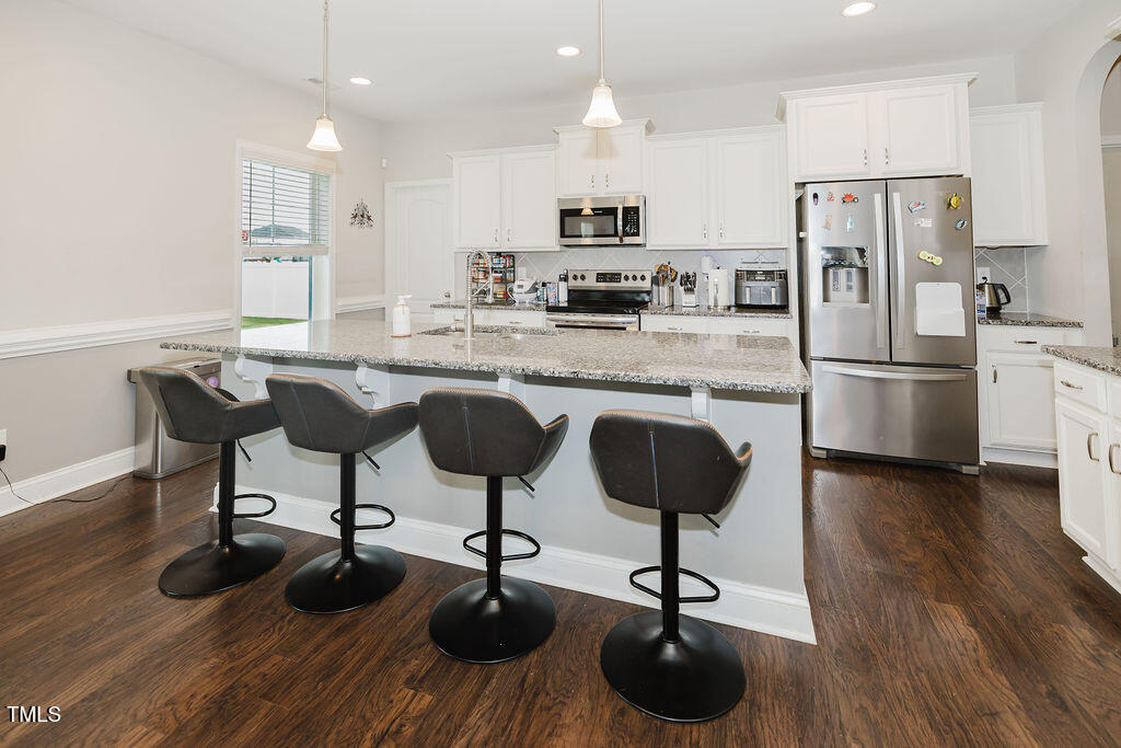105 Perignon Drive Princeton, NC 27569 - Photo 9 of 38 a kitchen with stainless steel appliances granite countertop a dining table chairs stove and refrigerator