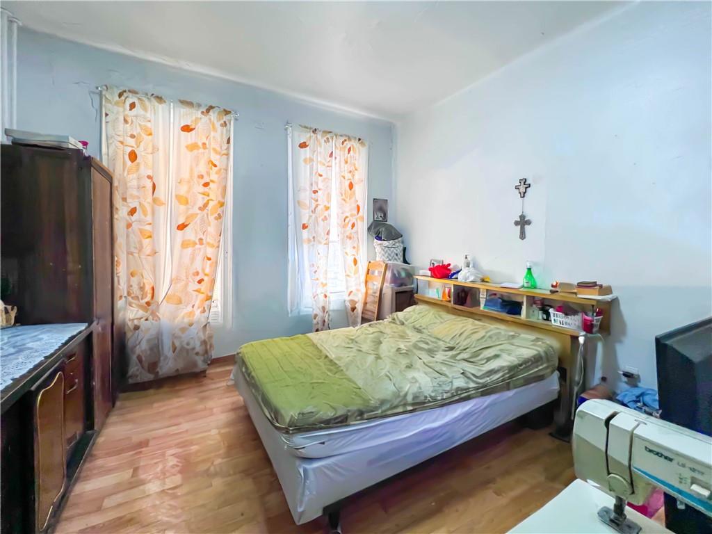 5907 4th Avenue Brooklyn, NY 11220 - Photo 15 of 37 a bedroom with a bed table and a flat tv screen