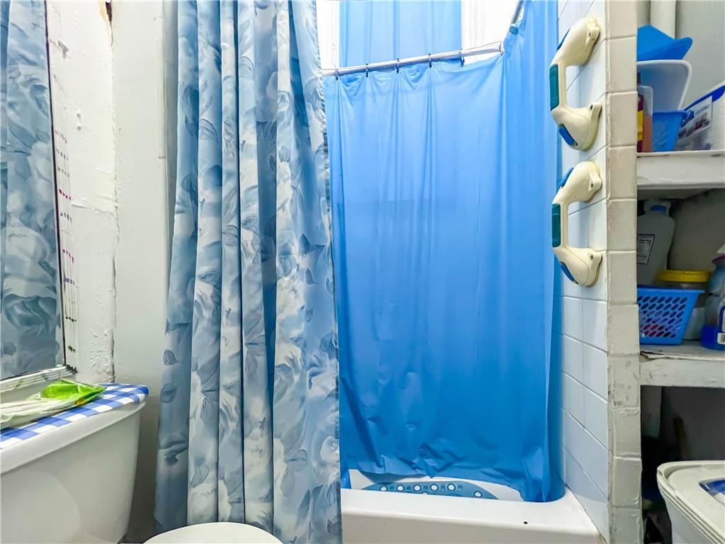 5907 4th Avenue Brooklyn, NY 11220 - Photo 19 of 37 a bathroom with a toilet and a shower curtain