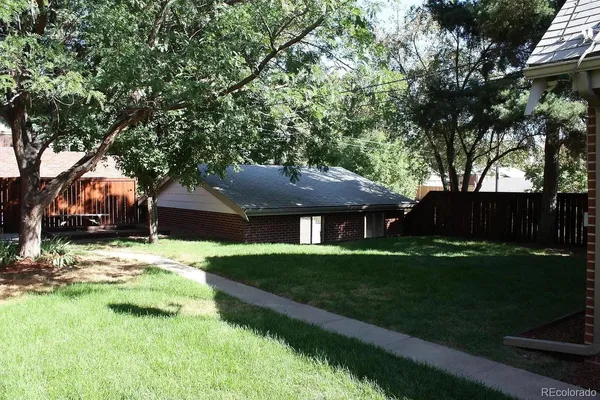 a view of house in front of a big yard with large trees