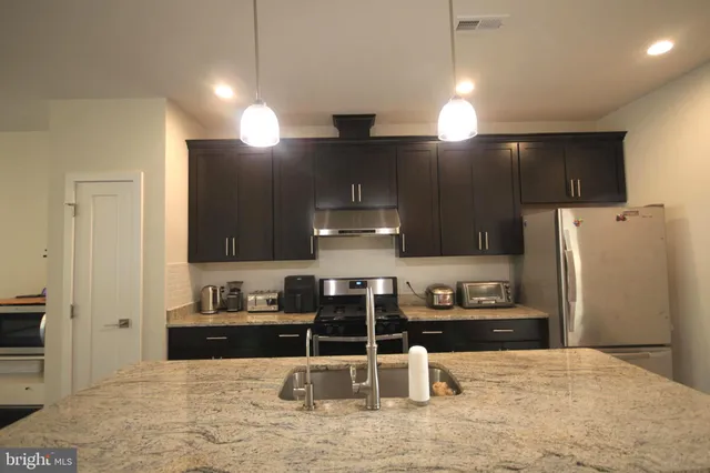 a kitchen with stainless steel appliances kitchen island granite countertop a refrigerator and a stove top oven