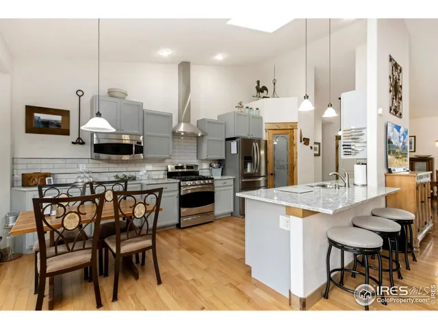 a kitchen with stainless steel appliances kitchen island granite countertop a table chairs sink and cabinets