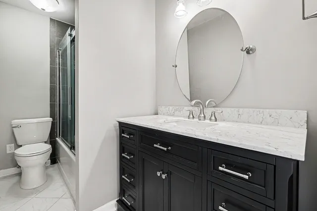 a bathroom with a granite countertop sink a toilet and a mirror