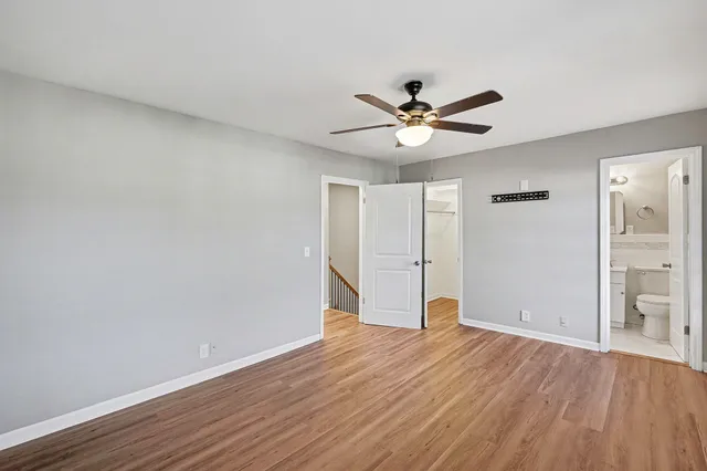 an empty room with wooden floor and ceiling fan