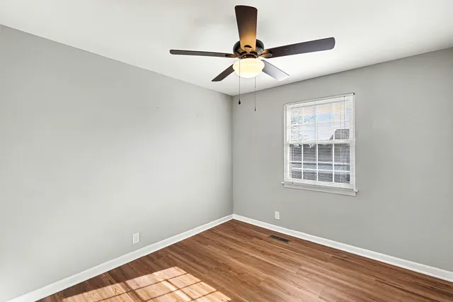 a view of empty room with wooden floor and fan