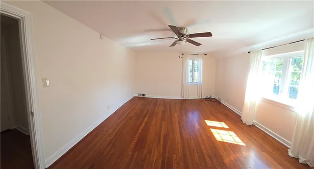 a view of empty room with wooden floor and fan