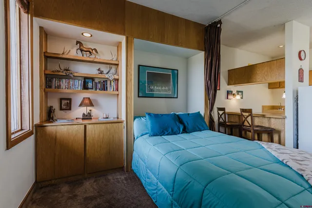 a bedroom with a bed and a bookshelf with wooden floor