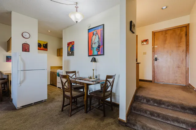 a view of a dining room with furniture and a refrigerator