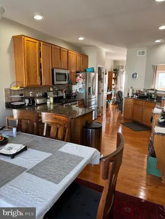 a kitchen with stainless steel appliances granite countertop a stove top oven a sink dishwasher a dining table and chairs with wooden floor