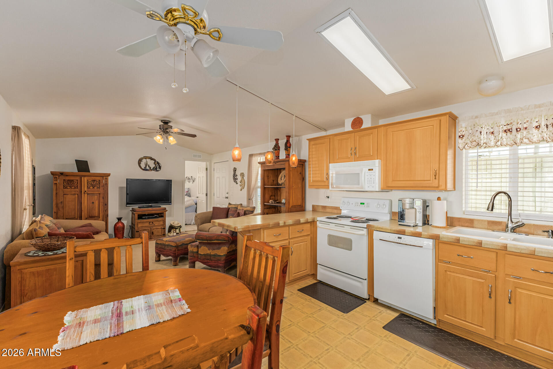 9302 East Broadway Road, Unit 186 Mesa, AZ 85208 - Photo 17 of 40 a large kitchen with kitchen island a large counter space appliances a sink and a living room view